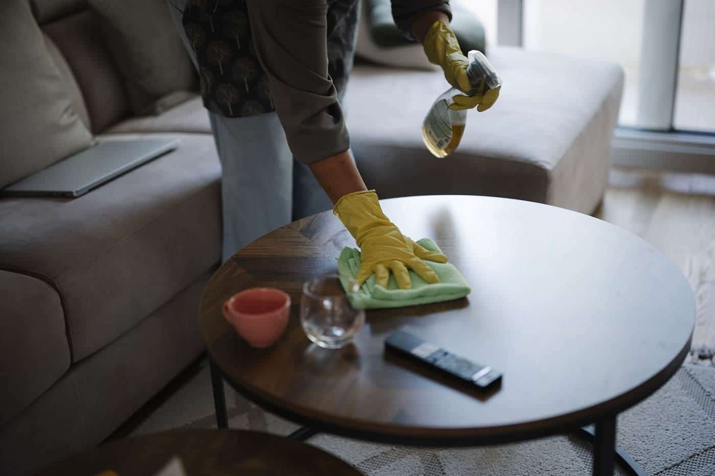 A person cleaning a coffee table with cleaning supplies
